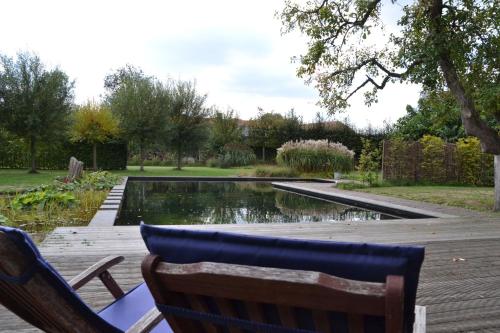a pool with two chairs next to a wooden deck at Vijverhoef in Ulicoten