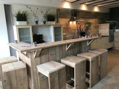 a large kitchen with a wooden counter with stools at Vijverhoef in Ulicoten
