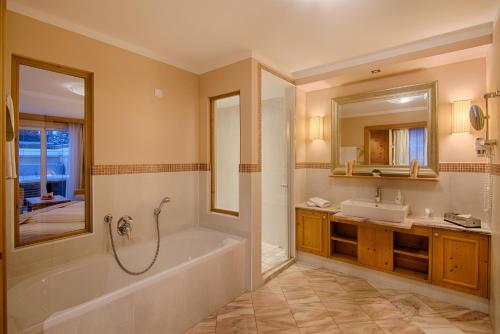 a bathroom with a tub and a sink and a mirror at Majestic - Unique Spa Resort in Brunico