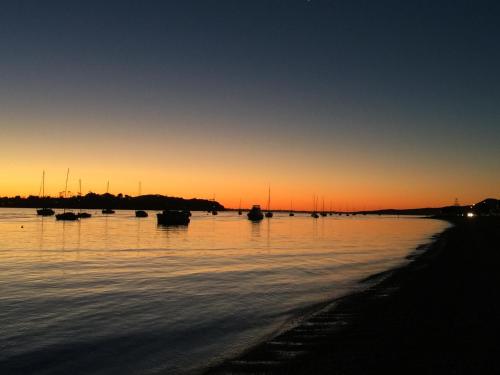 a sunset over a body of water with boats in it at Bucklands Beach Waterfront Motel in Auckland