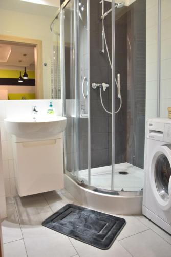 a bathroom with a shower and a sink and a washing machine at Apartament LATARNIKA in Jastrzębia Góra