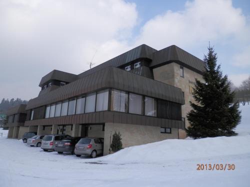 a building with cars parked in the snow at Horský Hotel Kubát in Benecko