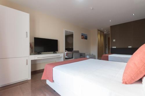 a bedroom with a white bed and a flat screen tv at Hotel Pradillo Conil in Conil de la Frontera