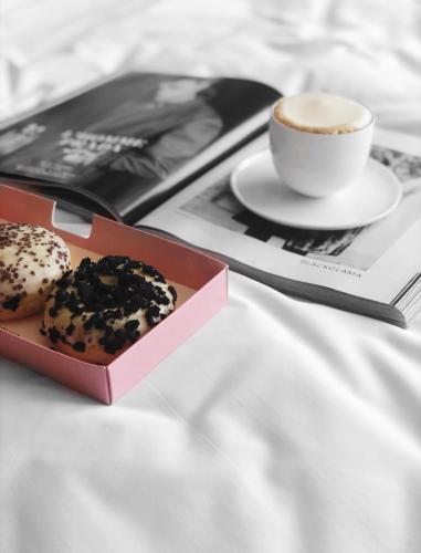 a cup of coffee and two donuts and a magazine at Link Hotel & Hub By Dan Hotels in Tel Aviv