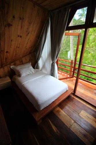 a bed in a room with a large window at Padi Ecolodge in Bukittinggi