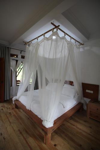 a bedroom with a bed with white mosquito net at Padi Ecolodge in Bukittinggi