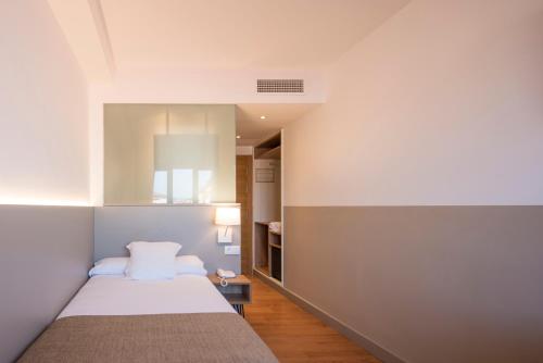 a small bedroom with a bed and a window at Hotel Airiños 3* in Cangas de Morrazo