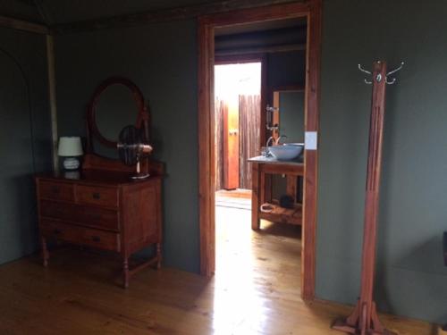 Zimmer mit einem Spiegel, einer Holzkommode und einem Spiegel in der Unterkunft Hillcrest Lodge Tents - Sandstone in Plettenberg Bay