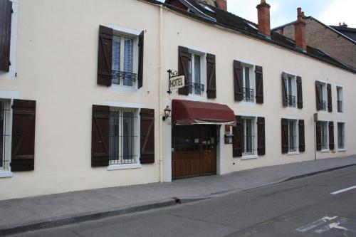 a white building with a brown door on a street at Hôtel République in Dijon