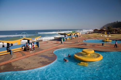 a large pool with people in it next to the beach at Ansteys Beach Self Catering Apartments in Durban