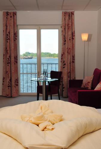 a large bed in a room with a view of the water at Hotel Müritzterrasse in Röbel