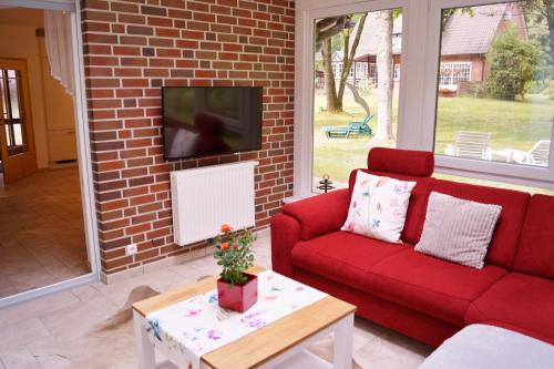 sala de estar con sofá rojo y TV en Ferienhaus Wahlers en Bispingen