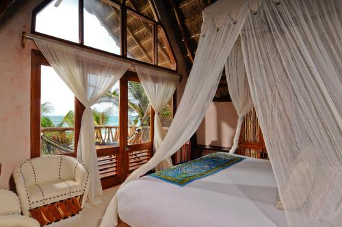 a bedroom with a bed and a chair and a window at Ahau Tulum - Beachfront Hotel in Tulum
