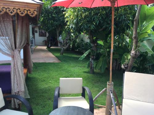 a patio with a red umbrella and two chairs at Naraya Homestay in San Pa Tong
