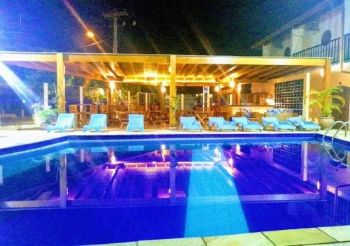 a swimming pool with white lounge chairs at Pousada Ilha Vitoria in Ubatuba