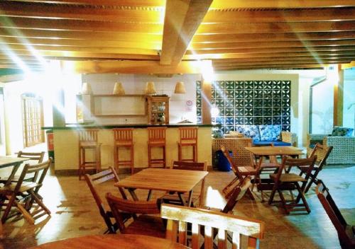 a restaurant with wooden tables and chairs and a counter at Pousada Ilha Vitoria in Ubatuba