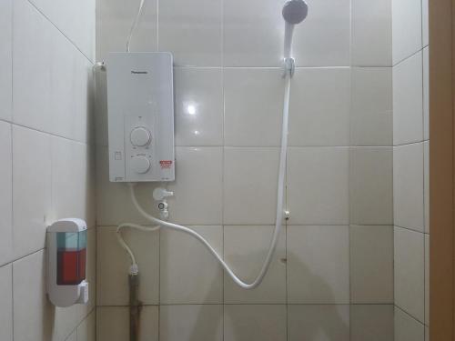 a shower in a bathroom with a phone on the wall at Tabun Homestay in Miri