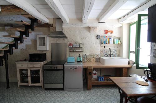 a kitchen with a stove and a sink and a table at gite au coeur des chateaux de la loire in Cour-sur-Loire