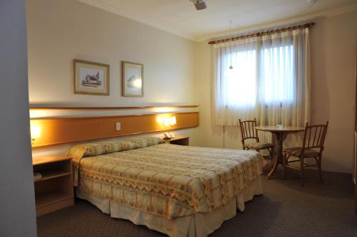 a hotel room with a bed and a table at Farina Park Hotel in Bento Gonçalves