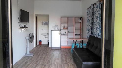 a living room with a couch and a table and a refrigerator at Lucky Home Prakhon Chai in Prakhon Chai