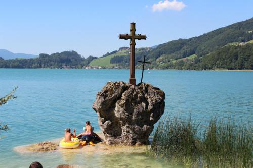 two people on a raft in the water near a rock with a cross at Ferienwohnung Claudia in Faistenau