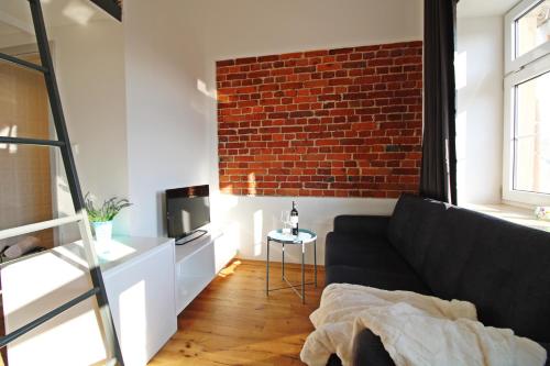 a living room with a black couch and a brick wall at Aparthotel Tectum TectumApartments in Wrocław