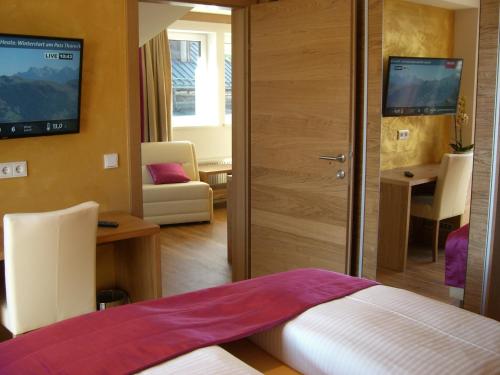 a bedroom with a bed and a desk and a television at Berger's Sporthotel in Saalbach Hinterglemm
