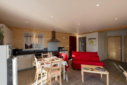 4 rue de la roque في Teissières-lès-Bouliès: مطبخ وغرفة معيشة مع أريكة حمراء