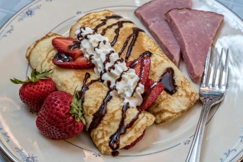 a plate of pancakes with strawberries and chocolate sauce at Silver Heart Inn & Cottages in Independence