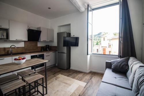 a kitchen and living room with a couch and a table at La Villa Tria Castella in Saint-Paul-Trois-Châteaux