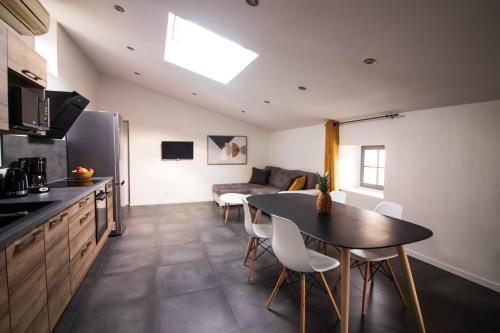 a kitchen and living room with a table and chairs at La Villa Tria Castella in Saint-Paul-Trois-Châteaux