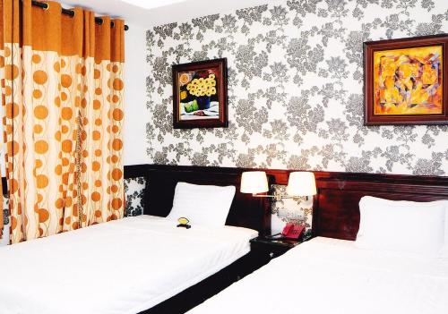a bedroom with two beds and a wall with wallpaper at Hoang Thanh Thuy Hotel 2 in Ho Chi Minh City