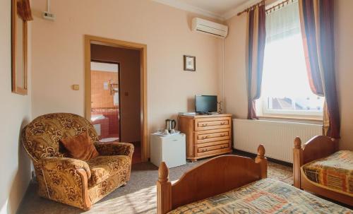 a bedroom with a chair and a bed and a television at Penzión Exclusive in Trenčín