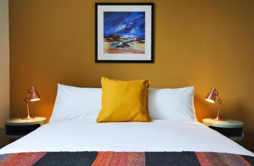 a bedroom with a bed with a yellow pillow and two lamps at The Five Turrets in Selkirk