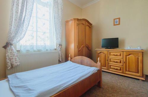 a bedroom with a bed and a tv and a dresser at Penzión Exclusive in Trenčín