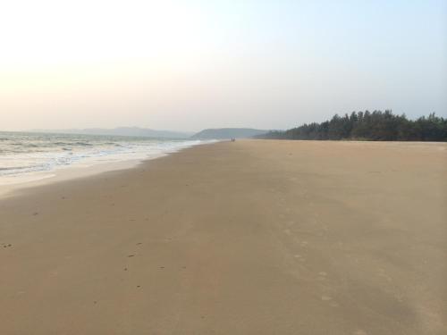 a beach with a person walking on the sand at OmBodhi Retreat in Kumta