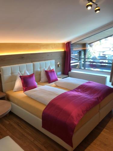 a bedroom with a large bed with purple pillows at Berger's Sporthotel in Saalbach Hinterglemm