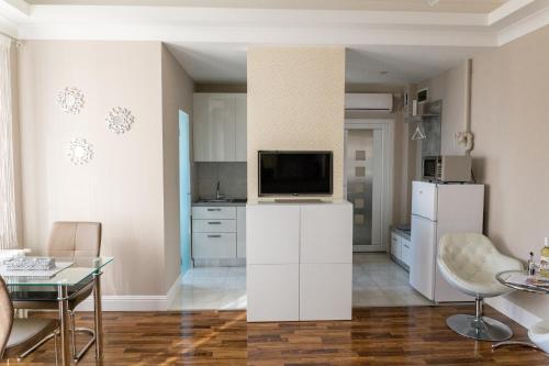 a living room with a white kitchen with a tv at Derin Apartman in Debrecen