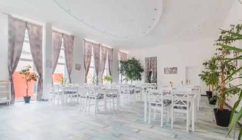 Zimmer mit weißen Tischen, Stühlen und Pflanzen in der Unterkunft Penzión Exclusive in Trenčín