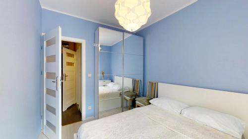 a blue bedroom with a bed and a mirror at Na Szancach 8E TectumApartments in Wrocław