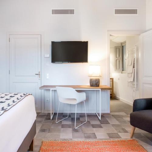a bedroom with a desk with a chair and a tv at Son Gris in Selva