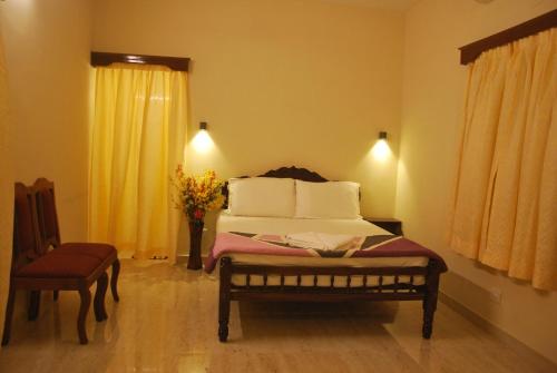 a bedroom with a bed and a chair and a window at Casa Feliz in Fort Kochi
