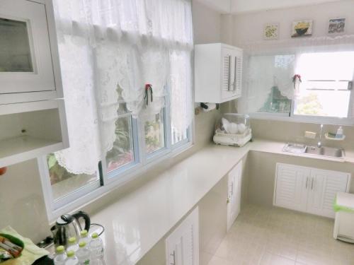 a white kitchen with white cabinets and windows at Green View 104 Khao Kho in Khao Kho