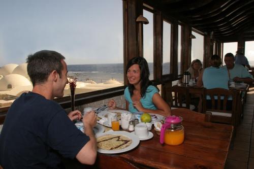 un hombre y una mujer sentados en una mesa comiendo comida en Nesima Resort, en Dahab