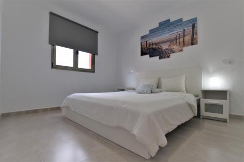 a white bedroom with a white bed and a window at Edificio Arinaga Golden in Arinaga