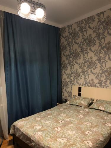 ウラジカフカスにあるОднокомнатная-двухуровневая квартираのベッドルーム(ベッド1台、青いカーテン付)