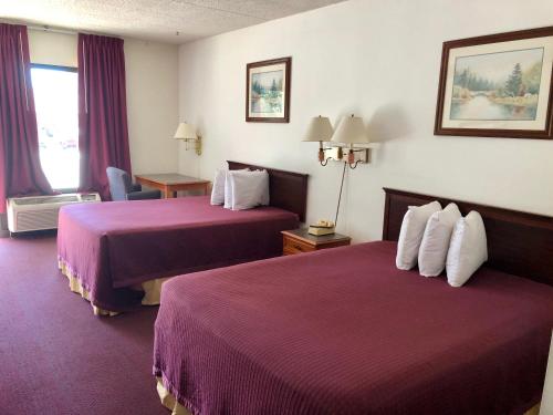 Habitación de hotel con 2 camas con sábanas moradas en Kewanee Motor Lodge en Kewanee
