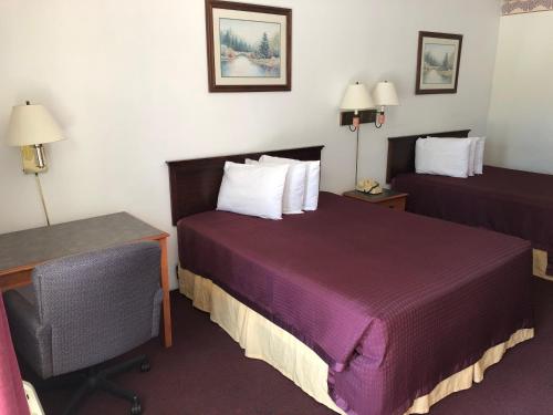 a hotel room with two beds and a desk at Kewanee Motor Lodge in Kewanee