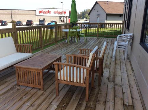 a wooden deck with chairs and a table and chairs at Scenic Shore Inn in Algoma