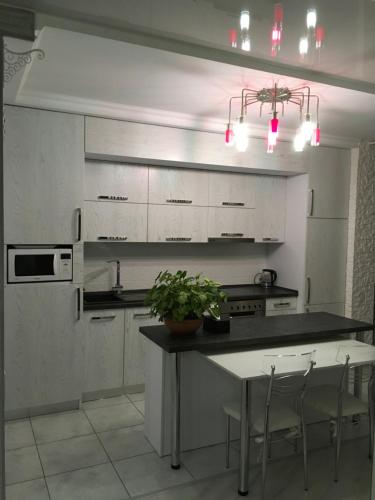 a kitchen with white cabinets and a table with chairs at Apartment Viliamsa in Odesa